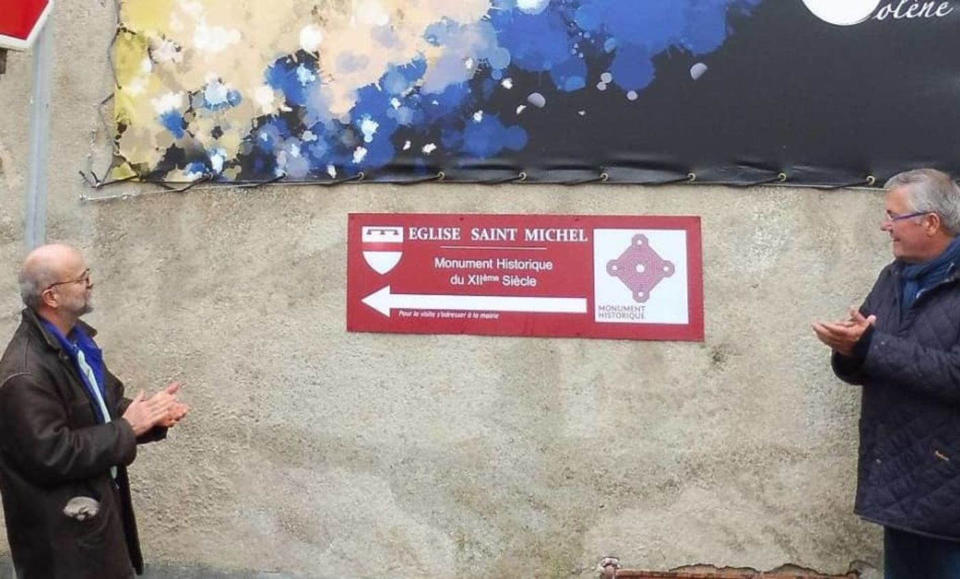 photo du panneau de l'installation dans la ville de Charost des peintures numérique représentant l’église de Charost, fresque réalisée par Solène Goget en 2022. Vue de face. L'artiste et professeur Nicolas Herubel y figure