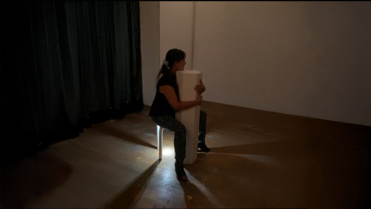 Une personne interagit avec le dispositif sonore immersive intitulée "Violoncelle" de Solène Goget (2021-2022). Ce dispositif sculptural invite le spectateur à s’asseoir à califourchon et à enlacer la structure, comme on le ferait avec un violoncelle. Une fois installé, une recomposition sonore d’une pièce de Ligeti est diffusée dans la structure. Les vibrations, transmises via un système interne de résonance, se propagent directement dans le thorax du visiteur. L’œuvre recrée la sensation physique de jouer d’un instrument à cordes, et transforme le corps du spectateur en caisse de résonance. Une expérience sensorielle intime, où la musique traverse littéralement le corps.