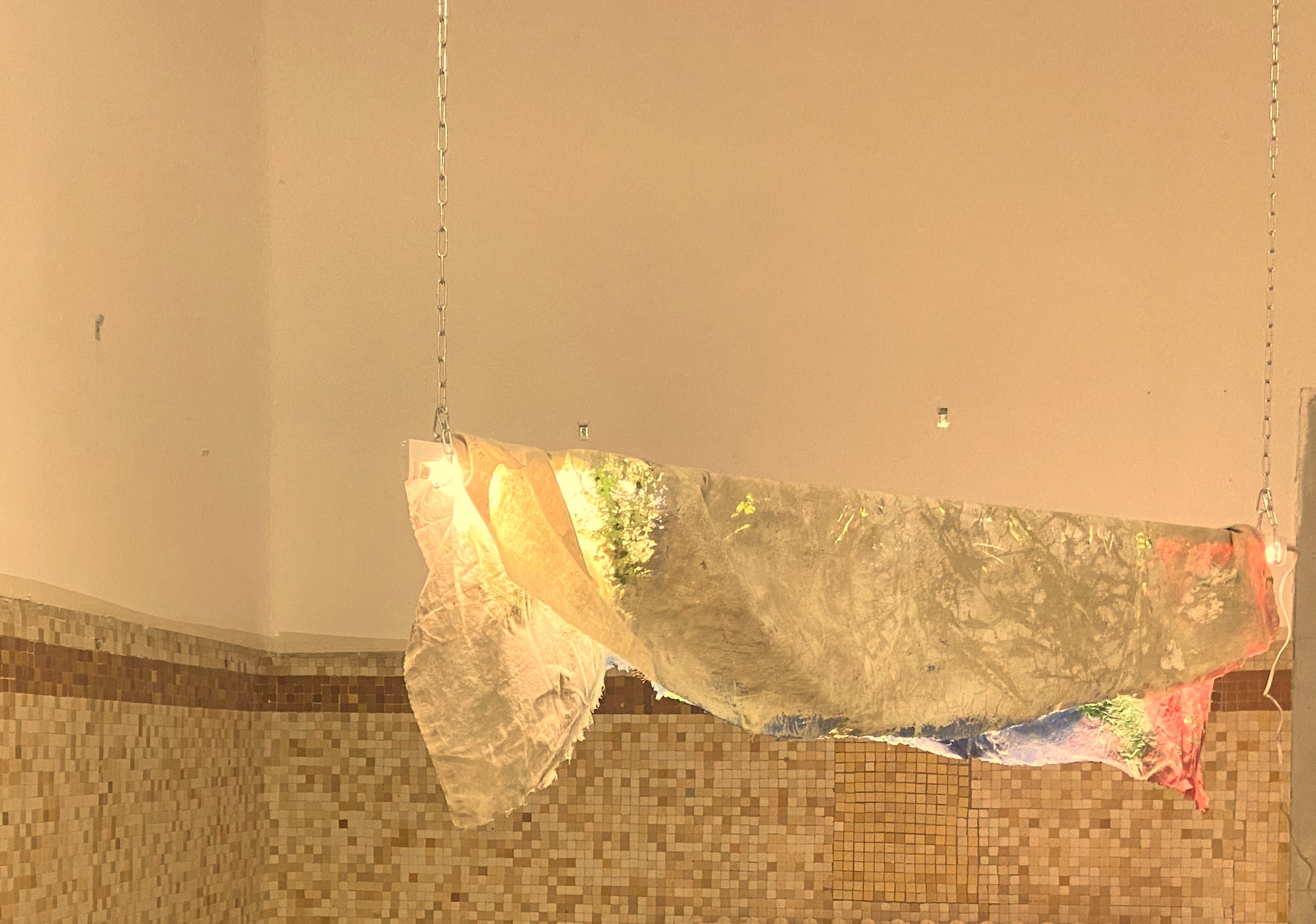 photo d'une des œuvres de l'exposition "trois jours a Groix". il s'agit d'un drap trouver sur l'île suspendu et arosé de lumière colorées. exposition avec Solène Goget.